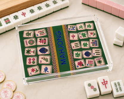 Mahjong game set with tiles and a green box on a light surface