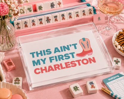 Mahjong game set with a sign reading 'This ain't my first Charleston' on a pink table.
