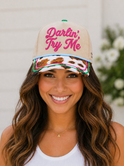 Woman wearing a beige cap with 'Darlin' Try Me' text, floral patterns, and colorful accents.