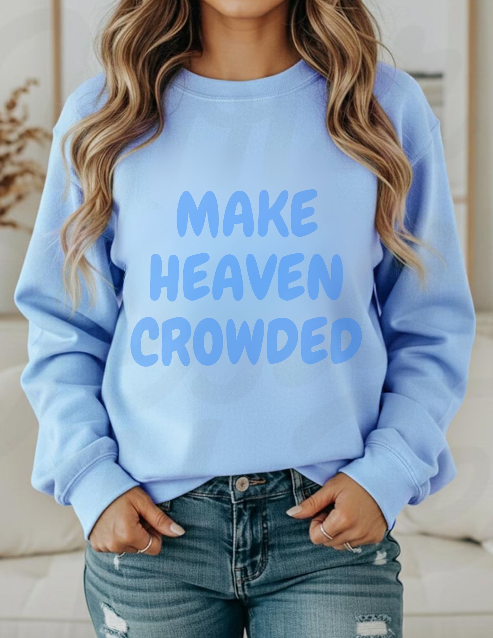 Light blue sweatshirt with 'MAKE HEAVEN CROWDED' text worn by a person.